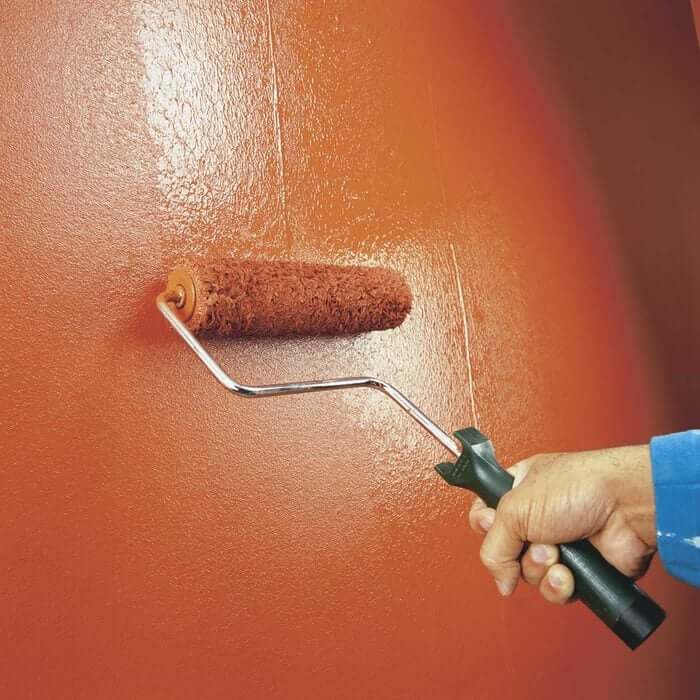 A painter carefully rolling paint onto a large wall